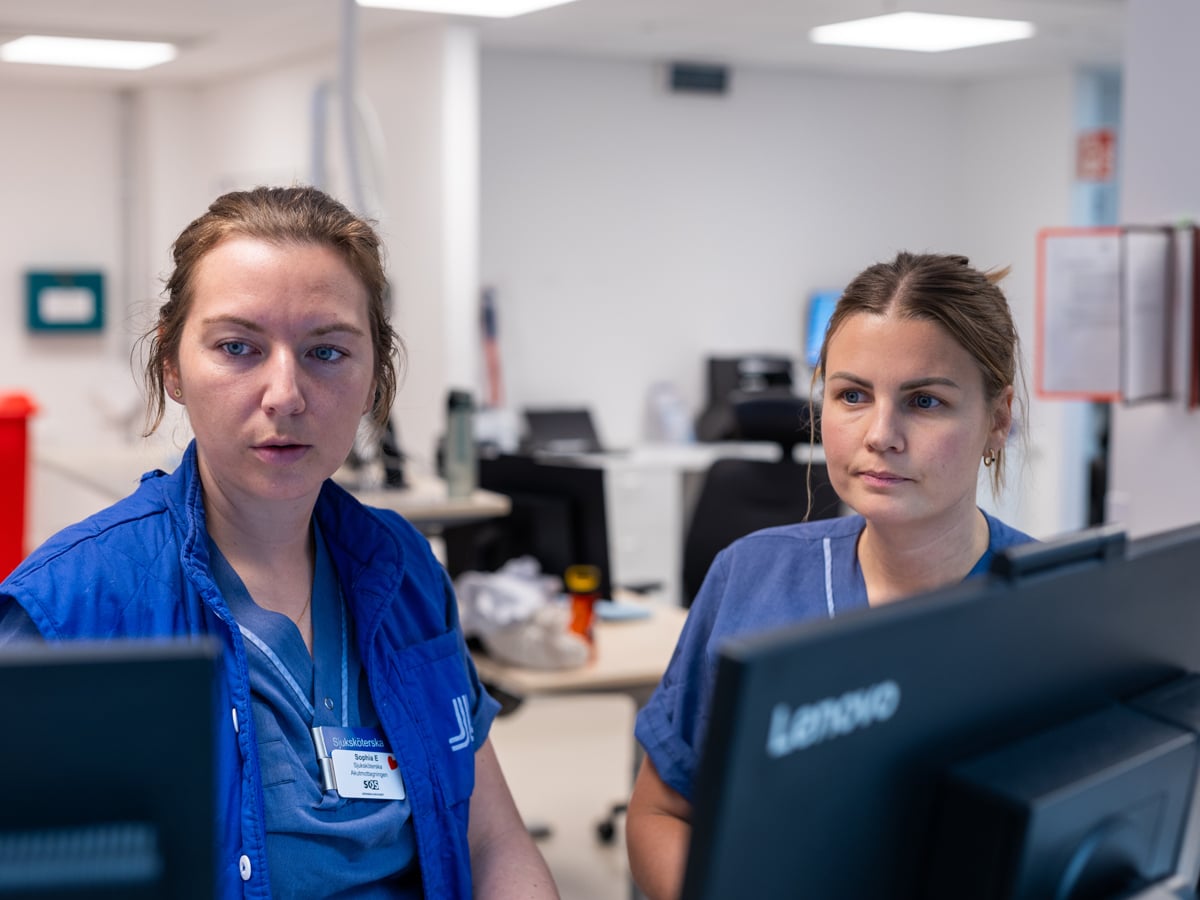 Två kvinnliga sjuksköterskor tittar på en dataskärm